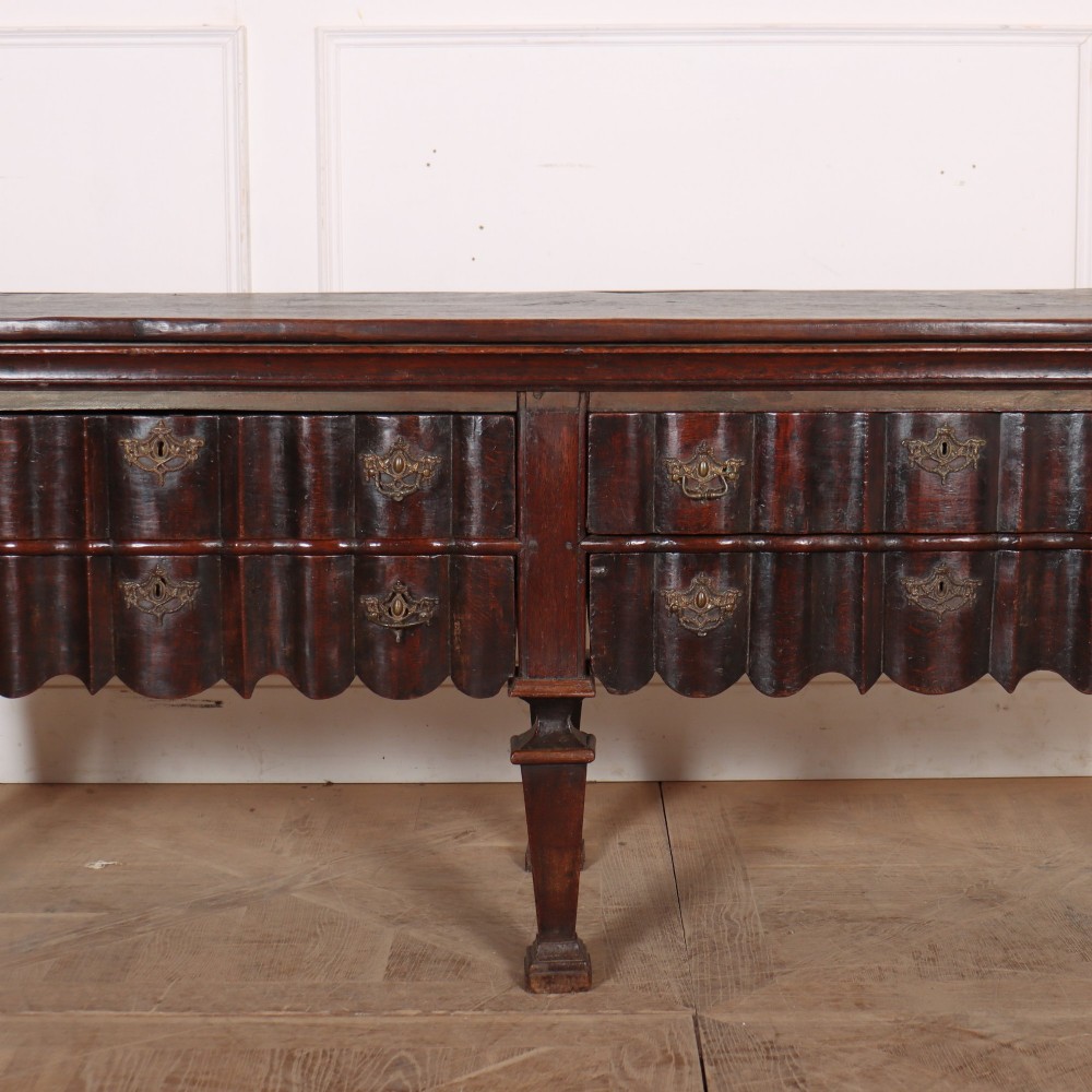 An antique dark oak Dutch dresser base with fluted drawer fronts, brass hardware, and turned legs. View III