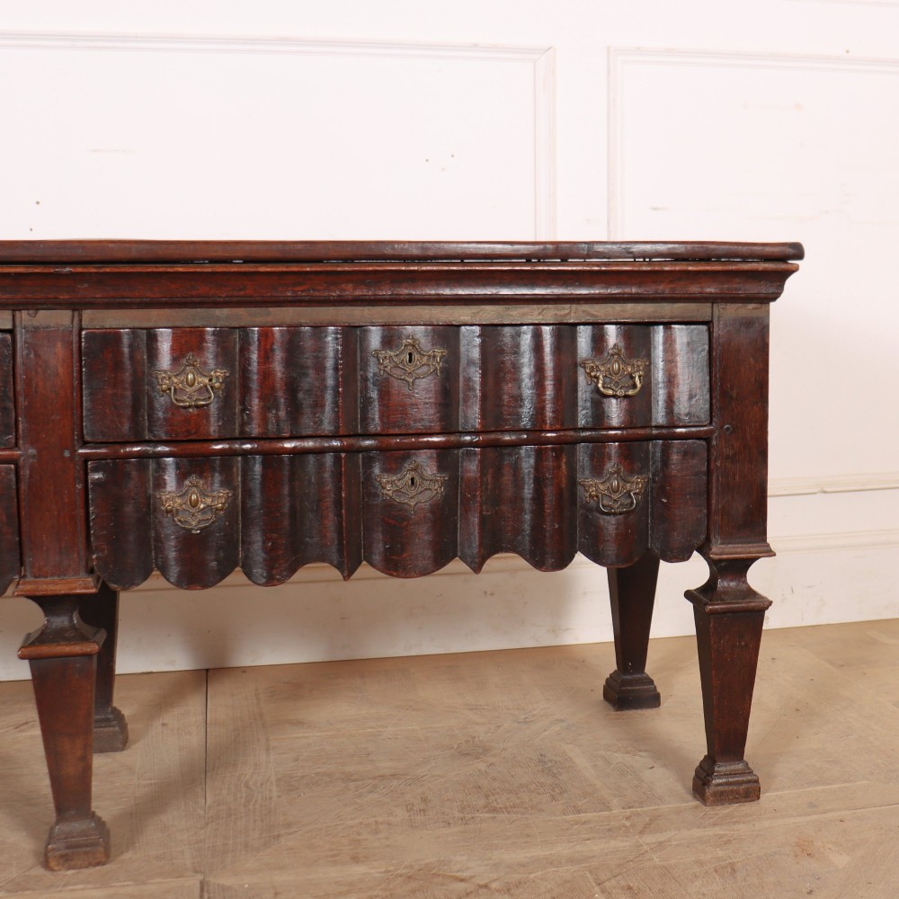 An antique dark oak Dutch dresser base with fluted drawer fronts, brass hardware, and turned legs. View IV