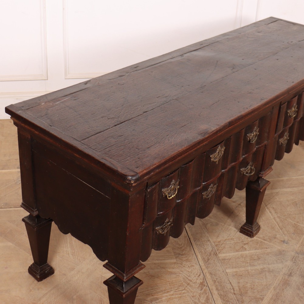 An antique dark oak Dutch dresser base with fluted drawer fronts, brass hardware, and turned legs. View VI