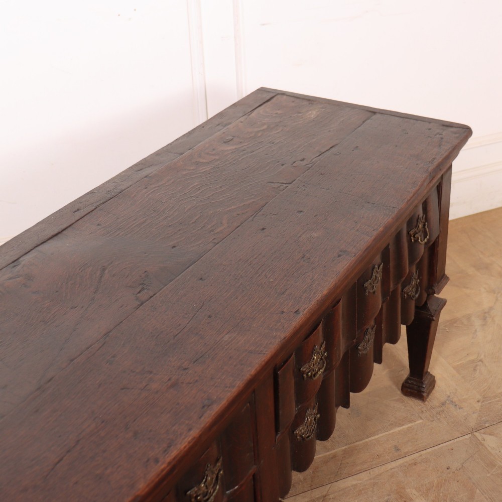 An antique dark oak Dutch dresser base with fluted drawer fronts, brass hardware, and turned legs. View VII