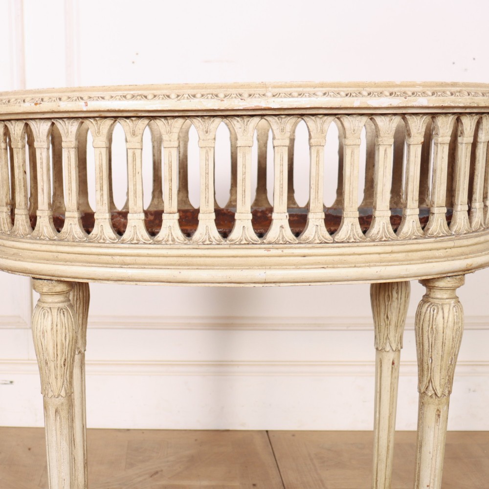 An oval cream painted antique jardiniere table featuring a pierced baluster gallery rim, slender carved legs, and a lower curved stretcher base. View II