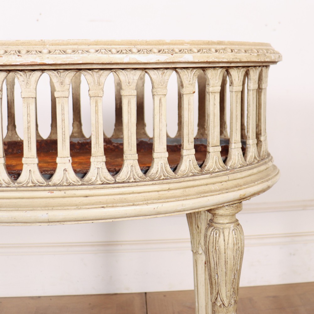 An oval cream painted antique jardiniere table featuring a pierced baluster gallery rim, slender carved legs, and a lower curved stretcher base. View V