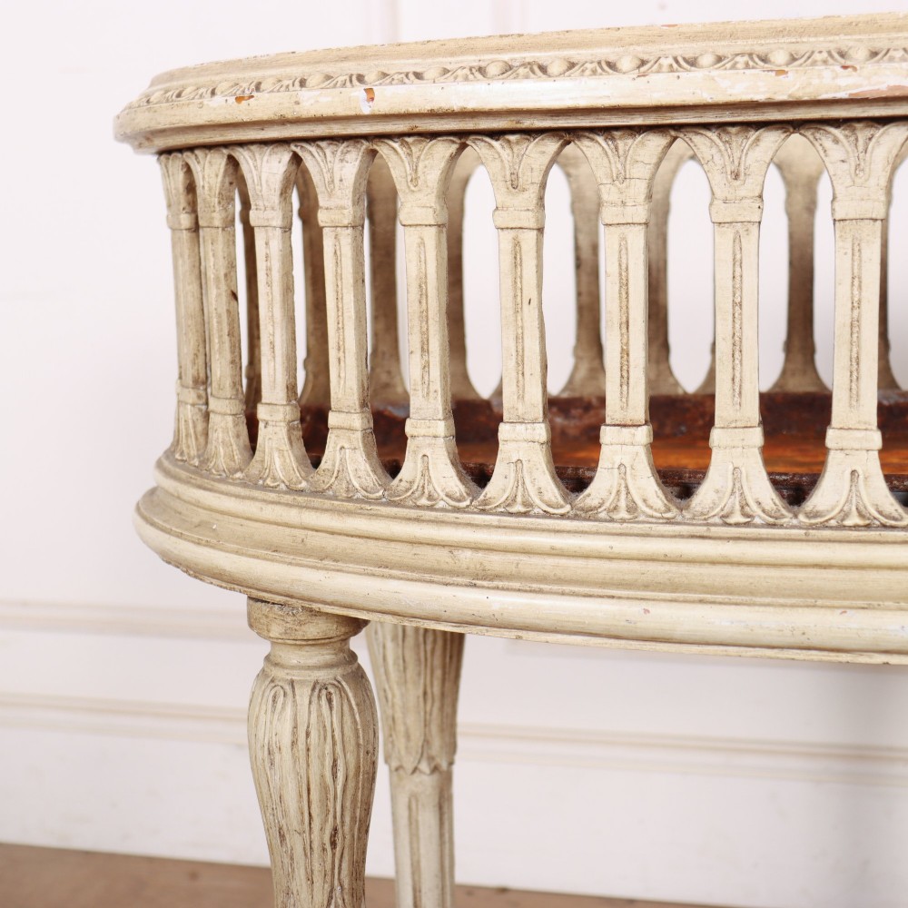 An oval cream painted antique jardiniere table featuring a pierced baluster gallery rim, slender carved legs, and a lower curved stretcher base. View VI