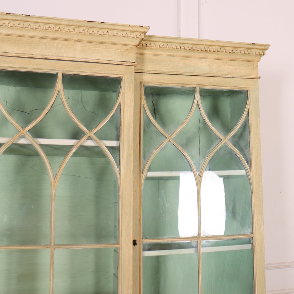 A nineteenth-century painted breakfront secretaire bookcase featuring upper Gothic astragal glazed doors over a green interior backdrop, above lower drawers and panelled cupboard doors. View III