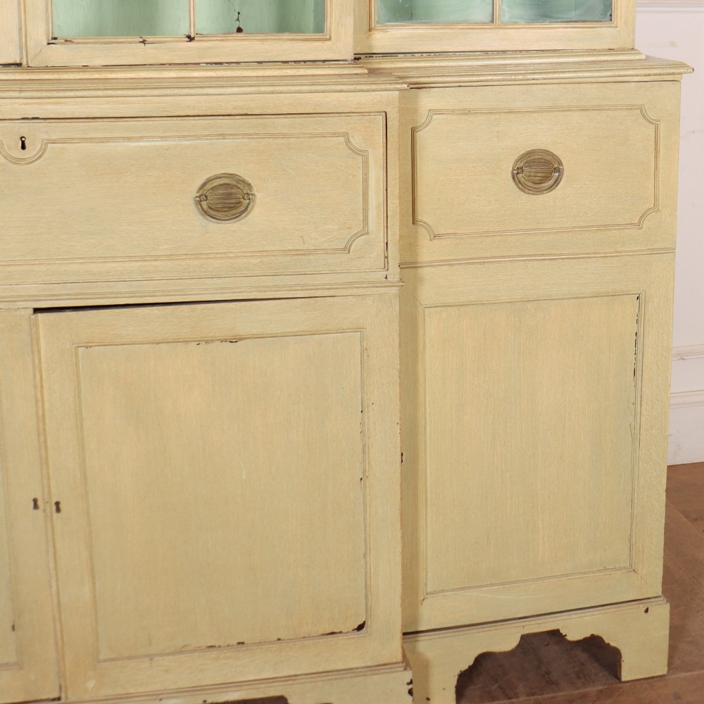 A nineteenth-century painted breakfront secretaire bookcase featuring upper Gothic astragal glazed doors over a green interior backdrop, above lower drawers and panelled cupboard doors. View V