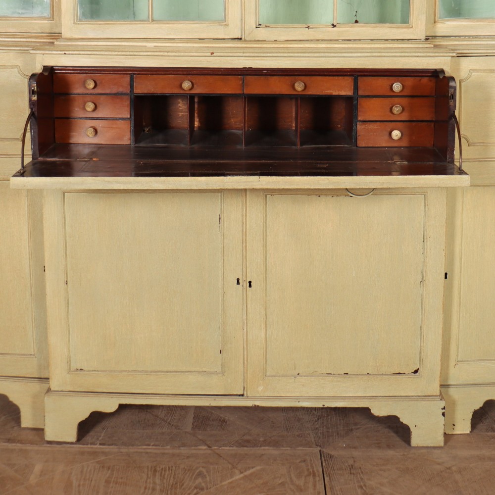 A nineteenth-century painted breakfront secretaire bookcase featuring upper Gothic astragal glazed doors over a green interior backdrop, above lower drawers and panelled cupboard doors. View VII