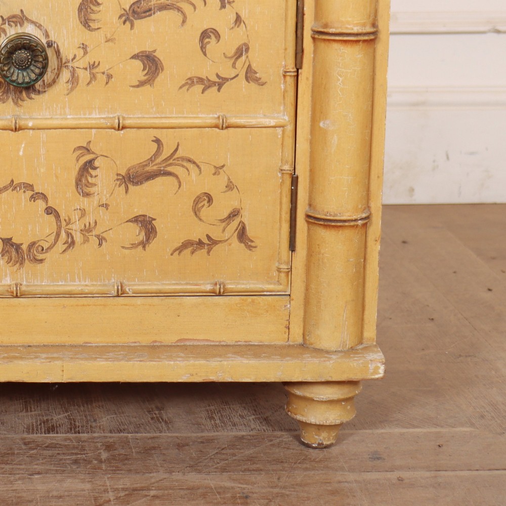 A pair of 19th-century pale yellow painted bedside cabinets featuring turned faux bamboo corner columns and hand-painted foliate motifs. View VII