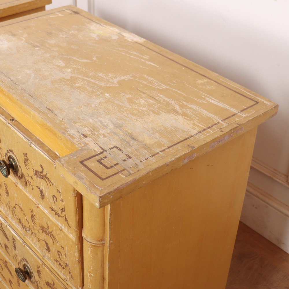 A pair of 19th-century pale yellow painted bedside cabinets featuring turned faux bamboo corner columns and hand-painted foliate motifs. View X