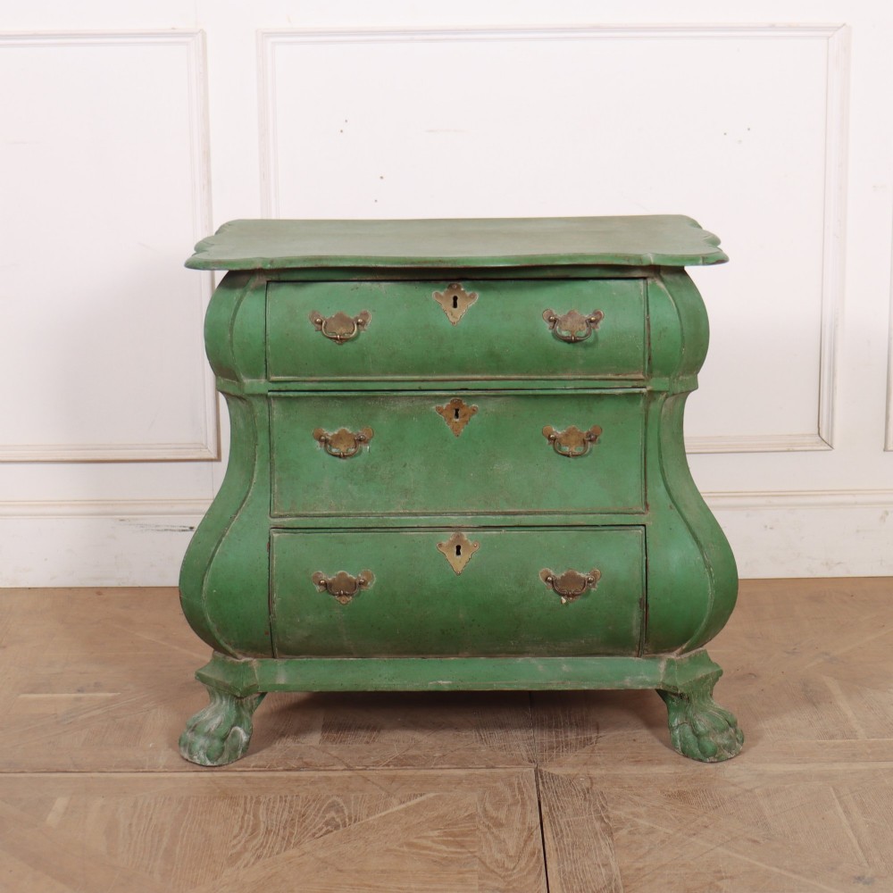 A green painted Dutch bombe commode with three drawers, brass drop handles, keyhole escutcheons, and carved feet.