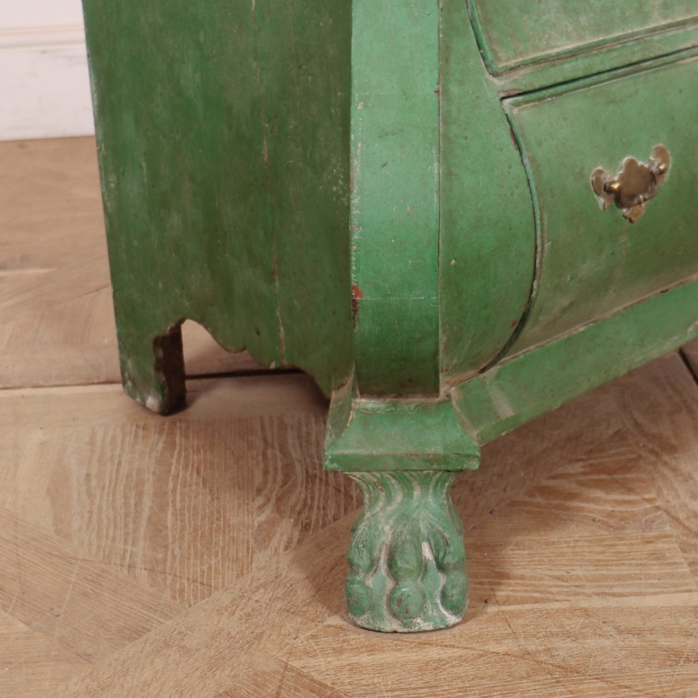 A green painted Dutch bombe commode with three drawers, brass drop handles, keyhole escutcheons, and carved feet. View VII