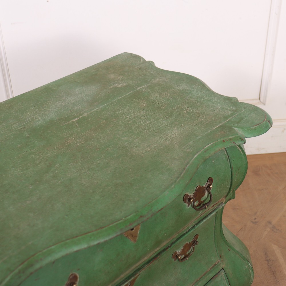 A green painted Dutch bombe commode with three drawers, brass drop handles, keyhole escutcheons, and carved feet. View IX