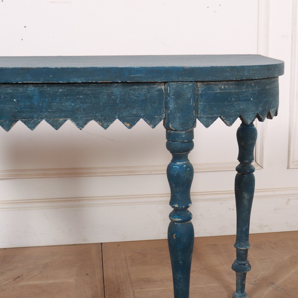 A blue painted wooden console table featuring rounded bow ends, a scalloped apron, and four turned legs. View III