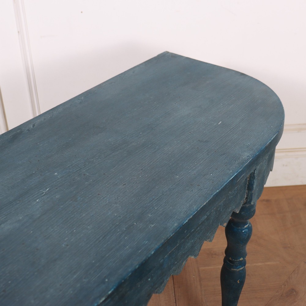 A blue painted wooden console table featuring rounded bow ends, a scalloped apron, and four turned legs. View VII