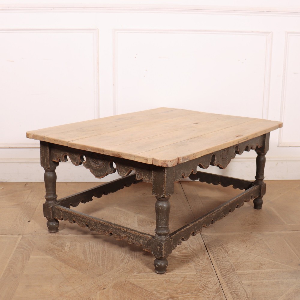 A low rectangular coffee table with a scrubbed pine top and dark painted frame featuring scalloped aprons, a carved shell motif, and turned legs. View V