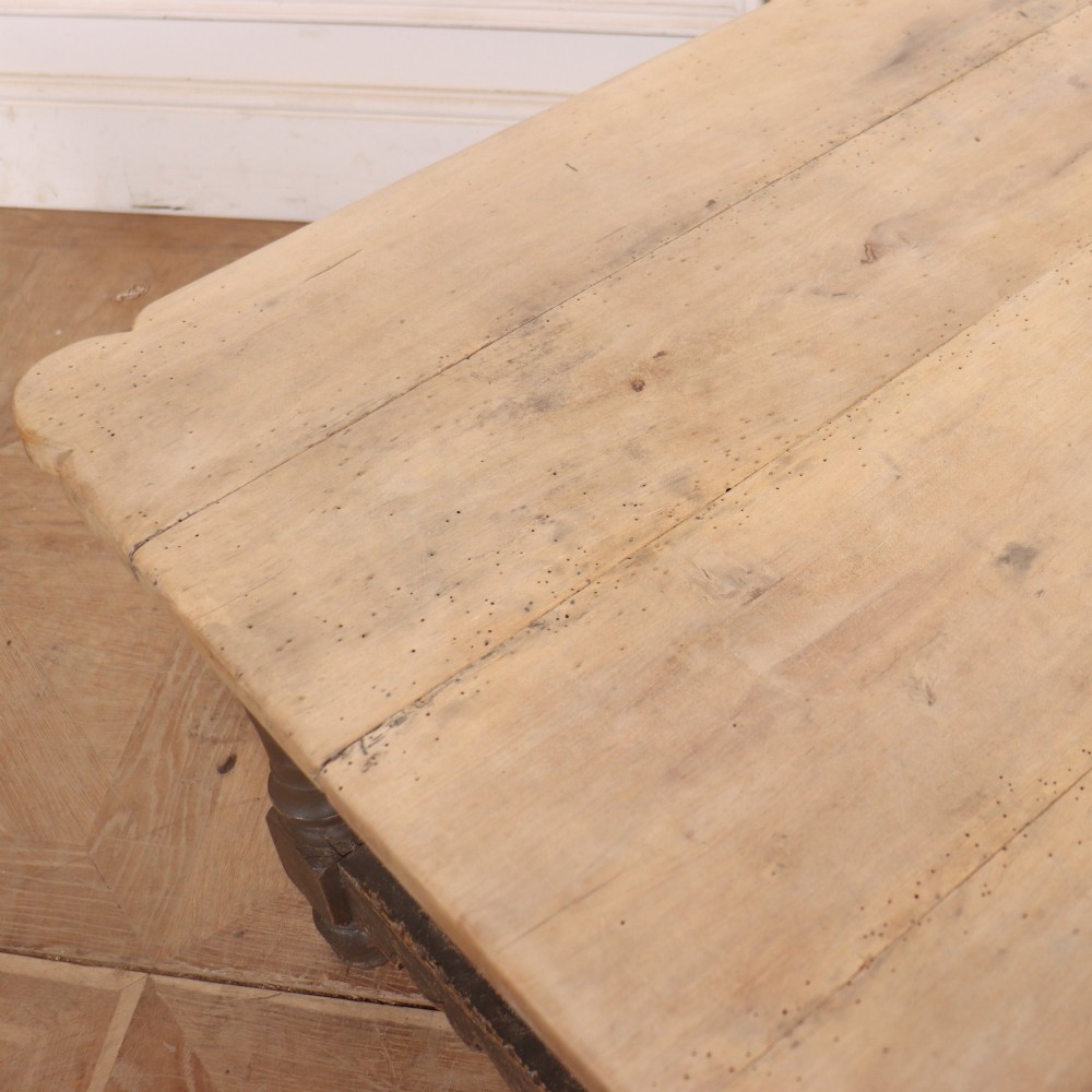 A low rectangular coffee table with a scrubbed pine top and dark painted frame featuring scalloped aprons, a carved shell motif, and turned legs. View X
