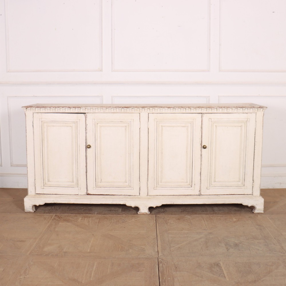 A long four-door Italian painted wooden enfilade with a distressed off-white finish, moulded cupboard panels, and bracket feet.
