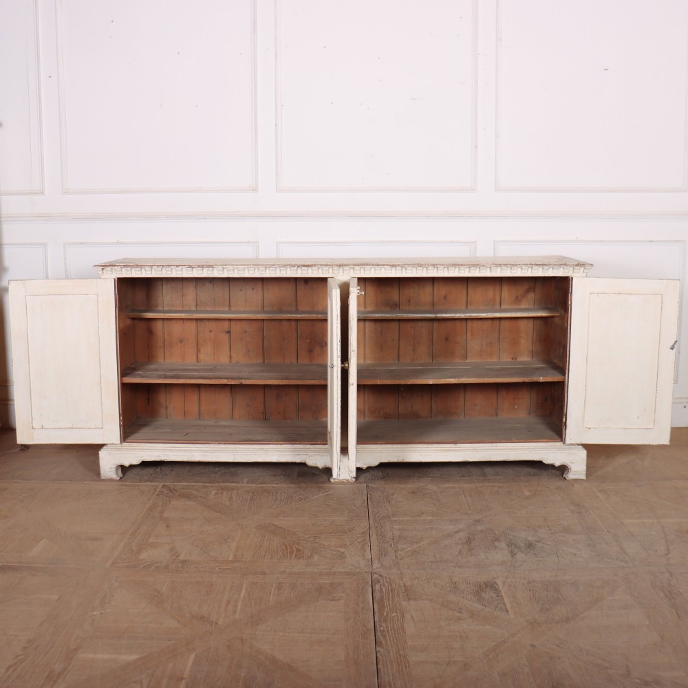 A long four-door Italian painted wooden enfilade with a distressed off-white finish, moulded cupboard panels, and bracket feet. View VII