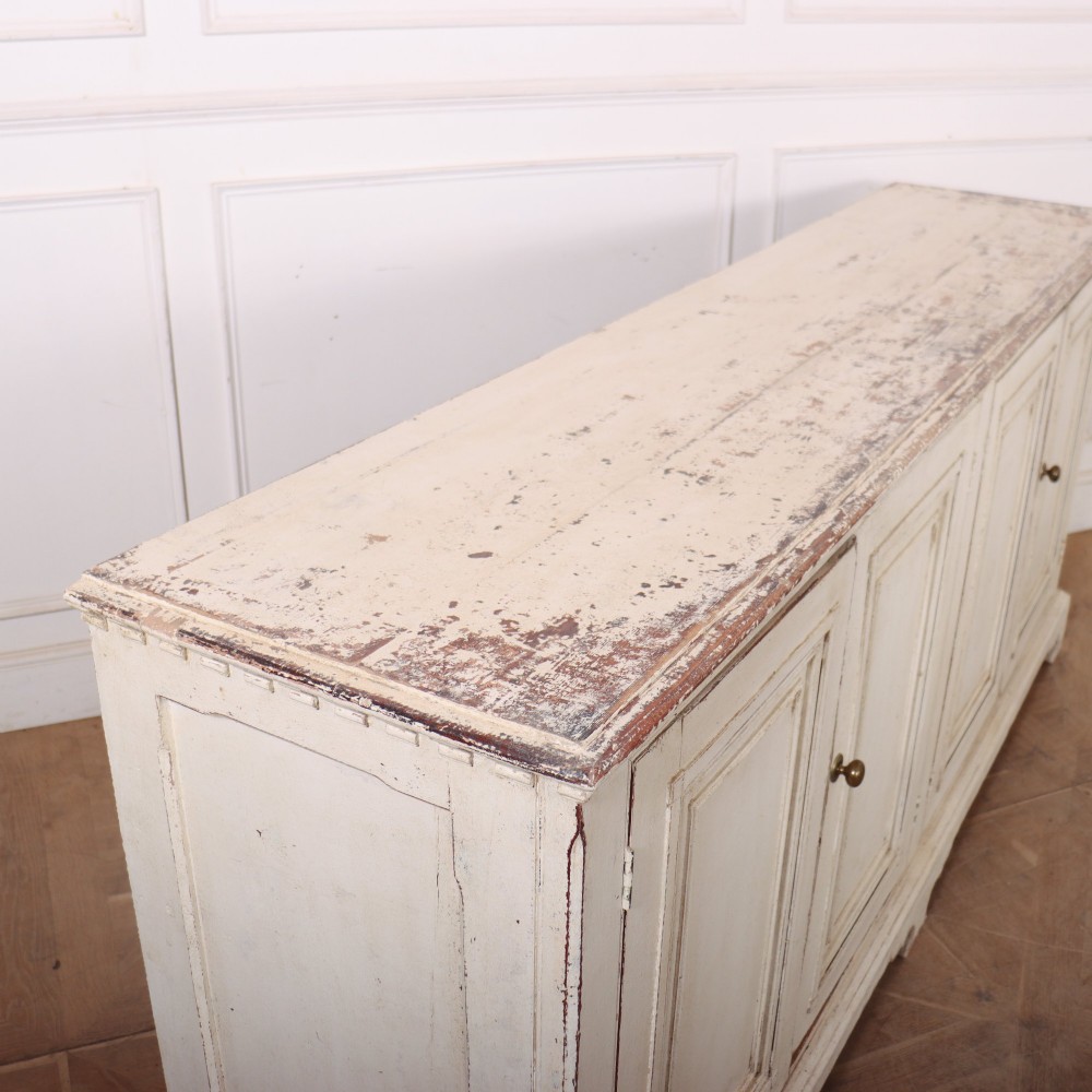A long four-door Italian painted wooden enfilade with a distressed off-white finish, moulded cupboard panels, and bracket feet. View IX
