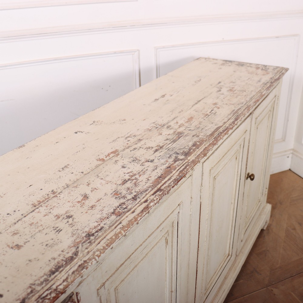 A long four-door Italian painted wooden enfilade with a distressed off-white finish, moulded cupboard panels, and bracket feet. View X