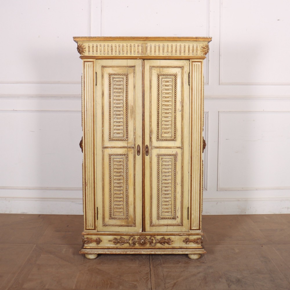 A late nineteenth-century Italian painted and gilded wooden cupboard featuring two tall doors with decorative carved panels, flanked by fluted pilasters on bun feet.