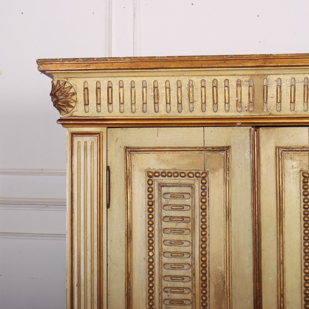A late nineteenth-century Italian painted and gilded wooden cupboard featuring two tall doors with decorative carved panels, flanked by fluted pilasters on bun feet. View II