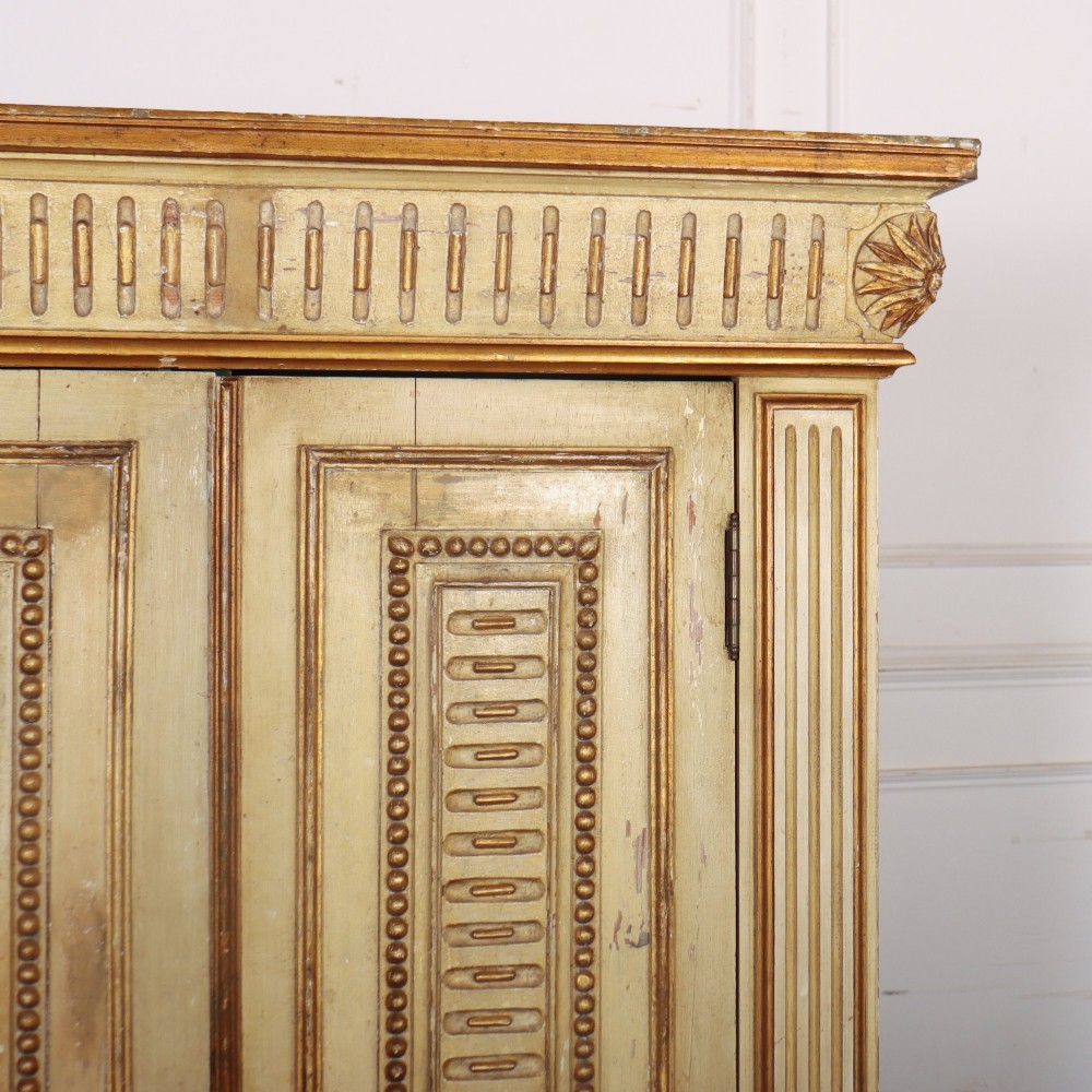A late nineteenth-century Italian painted and gilded wooden cupboard featuring two tall doors with decorative carved panels, flanked by fluted pilasters on bun feet. View III