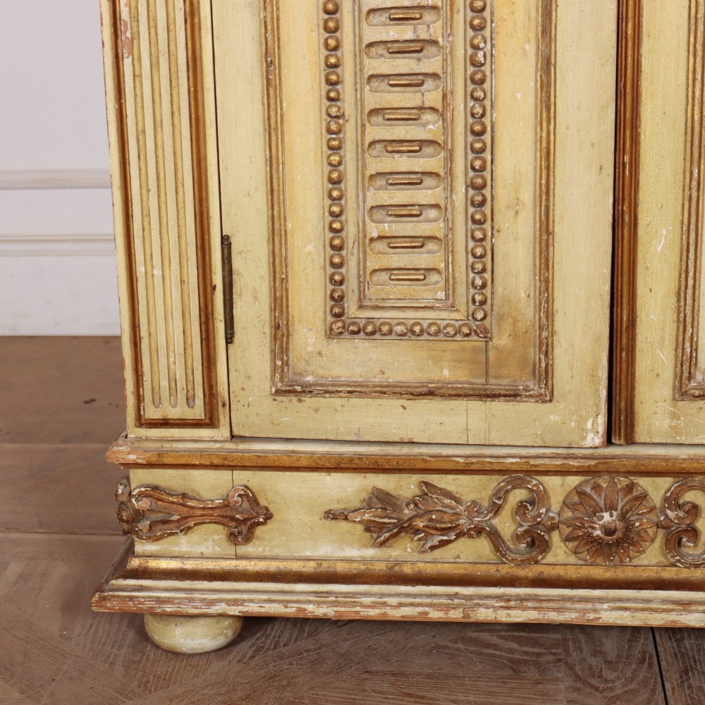 A late nineteenth-century Italian painted and gilded wooden cupboard featuring two tall doors with decorative carved panels, flanked by fluted pilasters on bun feet. View IV