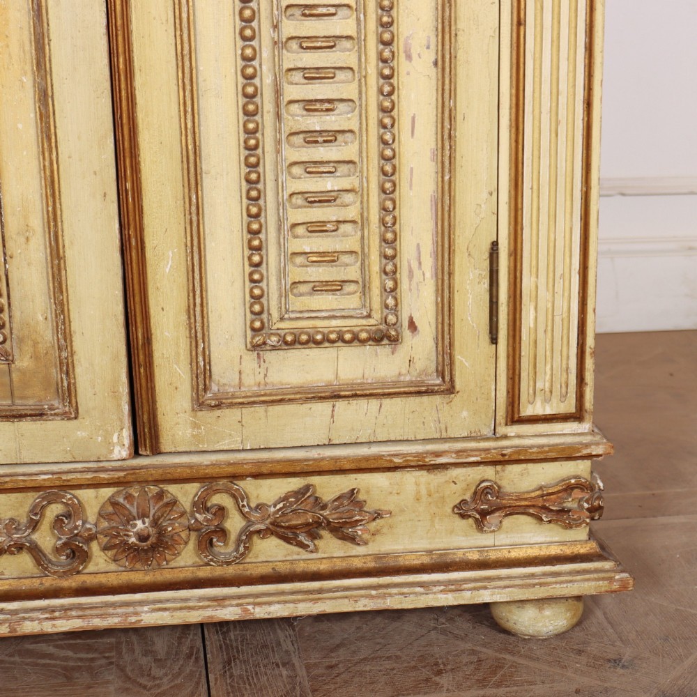 A late nineteenth-century Italian painted and gilded wooden cupboard featuring two tall doors with decorative carved panels, flanked by fluted pilasters on bun feet. View V