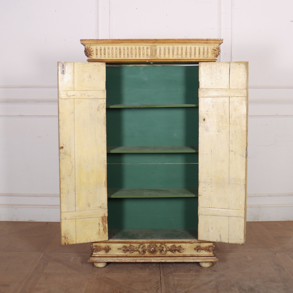 A late nineteenth-century Italian painted and gilded wooden cupboard featuring two tall doors with decorative carved panels, flanked by fluted pilasters on bun feet. View VII