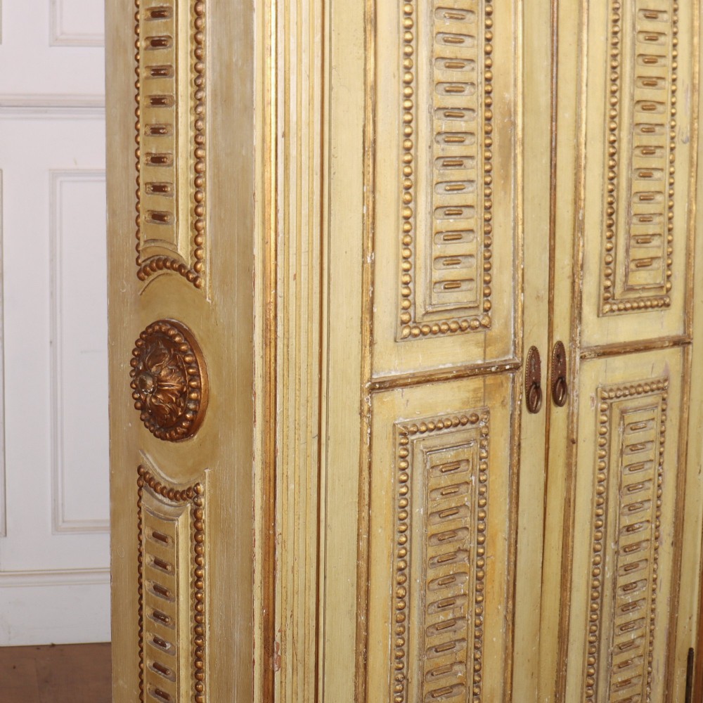 A late nineteenth-century Italian painted and gilded wooden cupboard featuring two tall doors with decorative carved panels, flanked by fluted pilasters on bun feet. View X