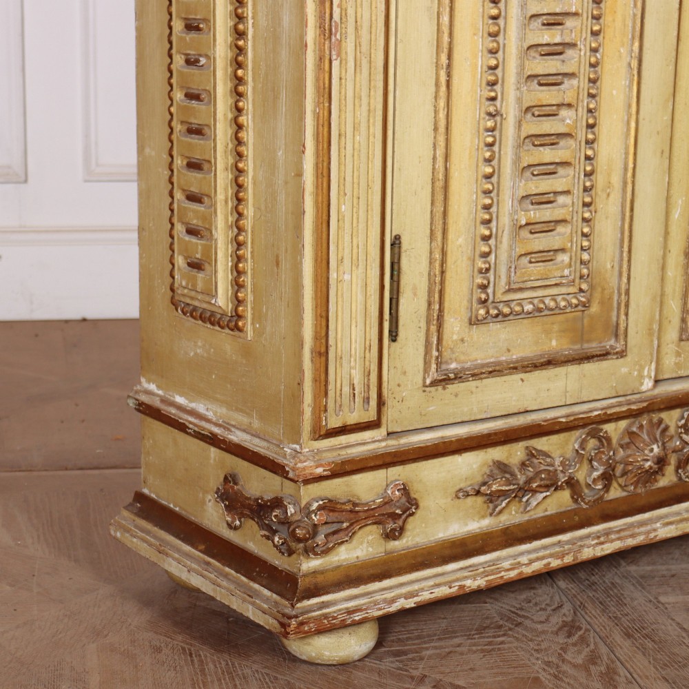 A late nineteenth-century Italian painted and gilded wooden cupboard featuring two tall doors with decorative carved panels, flanked by fluted pilasters on bun feet. View XI