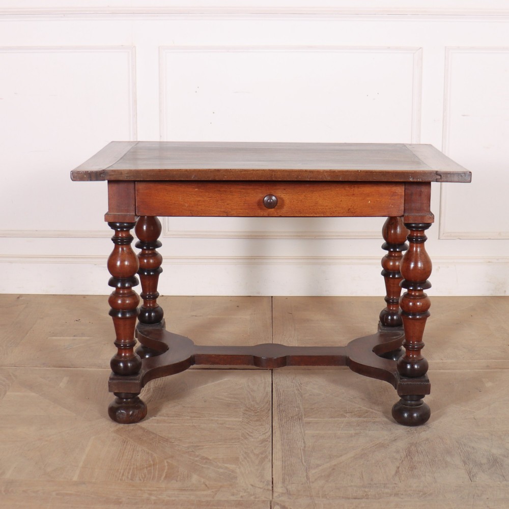 A warm brown wooden Italian side table desk featuring a single drawer with a round knob, heavy turned legs, and a shaped stretcher base.