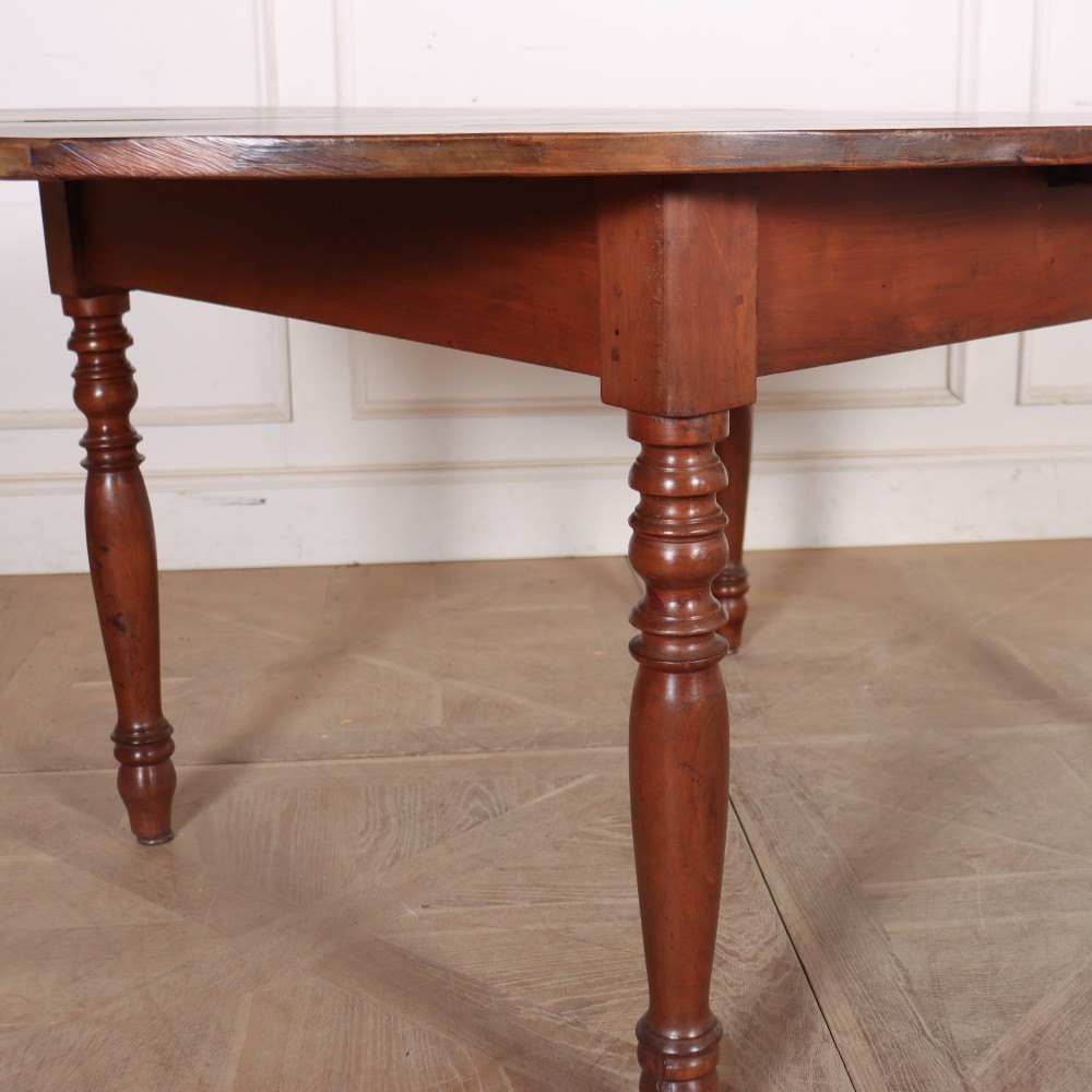 An antique French provincial dining table crafted from warm brown wood, featuring an oval top supported by four turned legs. View II