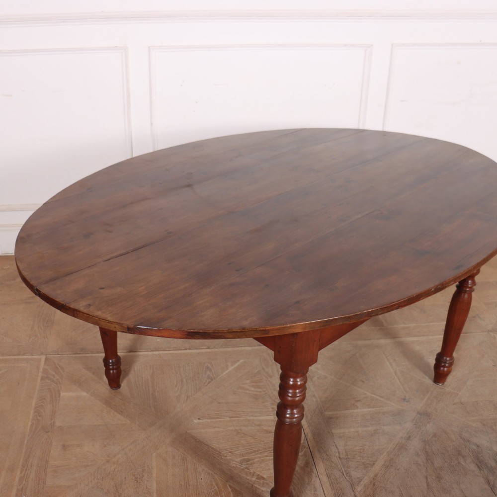 An antique French provincial dining table crafted from warm brown wood, featuring an oval top supported by four turned legs. View IV