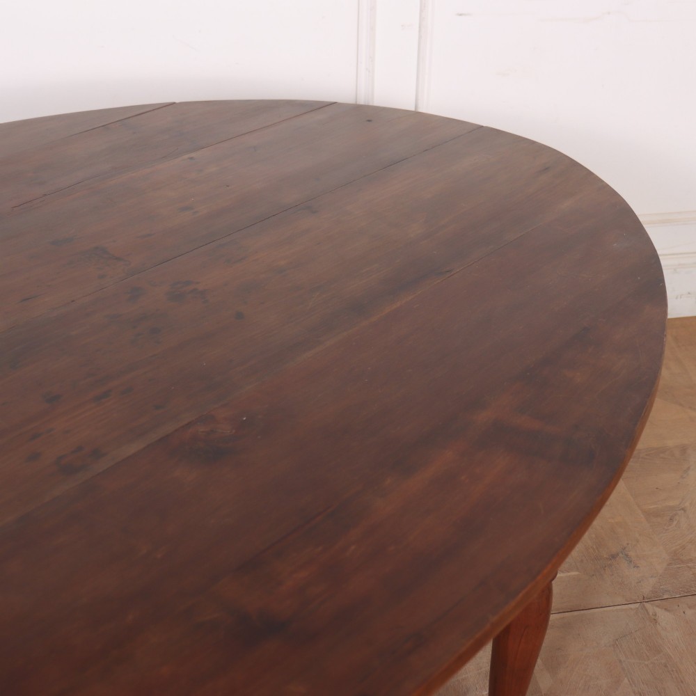 An antique French provincial dining table crafted from warm brown wood, featuring an oval top supported by four turned legs. View V