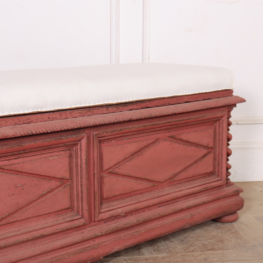 A long 19th-century Italian painted wooden bench featuring terracotta-coloured carved diamond panels, spiral corner columns, and a cream upholstered top seat cushion. View III