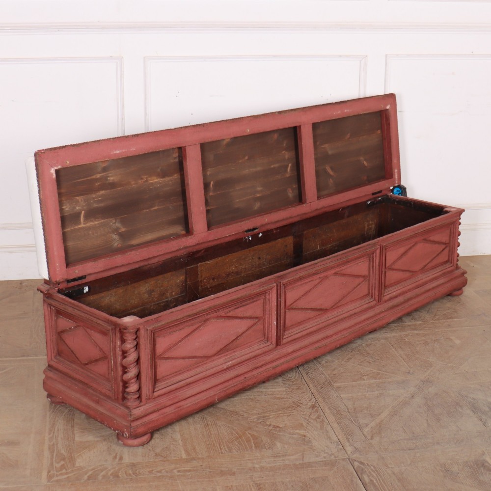 A long 19th-century Italian painted wooden bench featuring terracotta-coloured carved diamond panels, spiral corner columns, and a cream upholstered top seat cushion. View VII