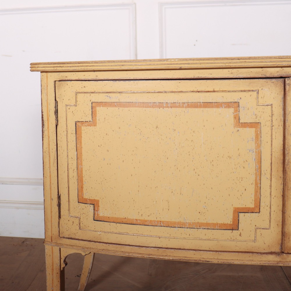 An antique English painted side cabinet in pale yellow with geometric orange door borders and tapered legs. View III