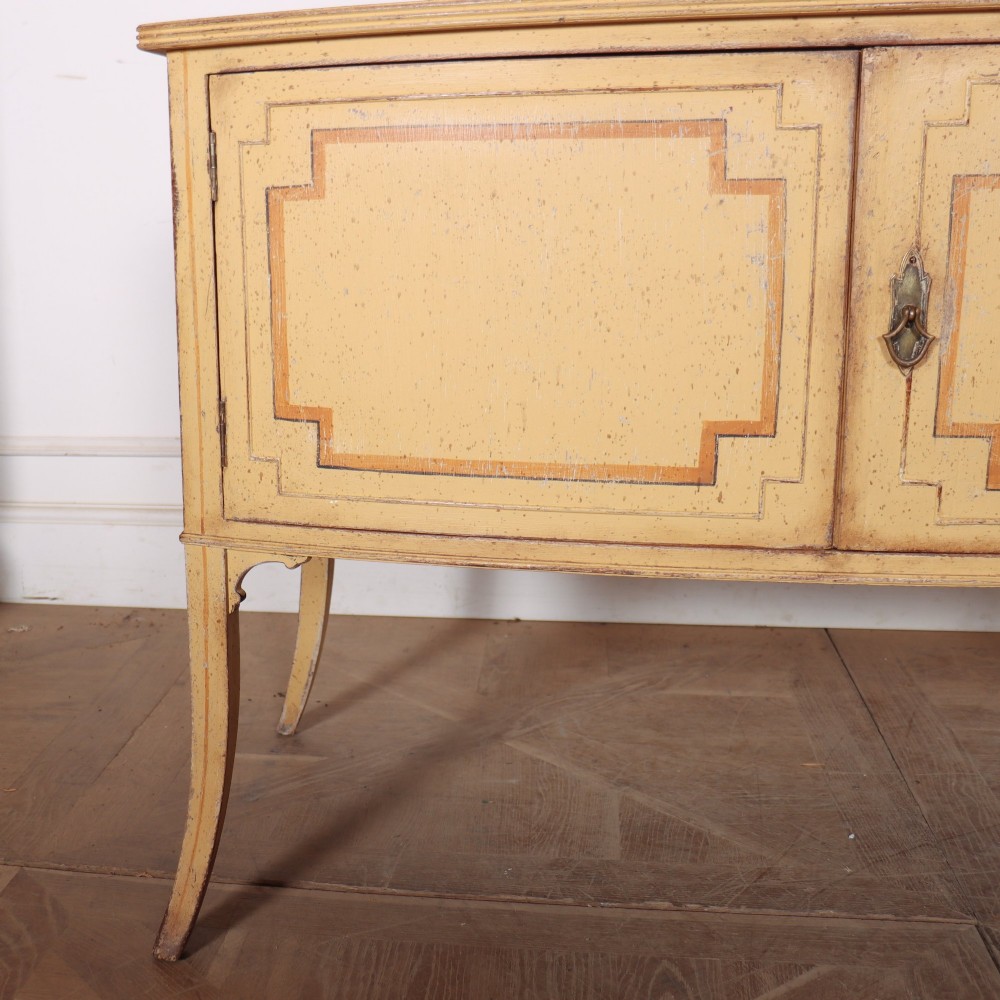An antique English painted side cabinet in pale yellow with geometric orange door borders and tapered legs. View IV