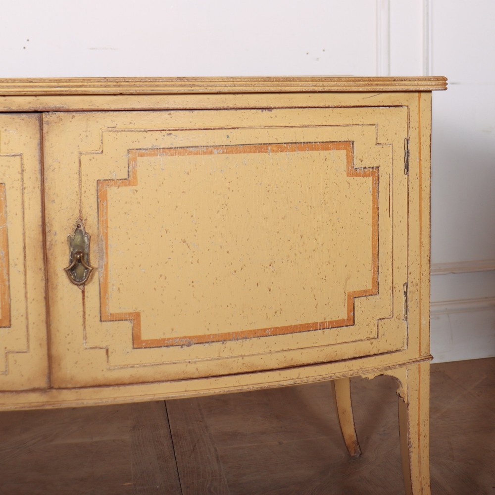 An antique English painted side cabinet in pale yellow with geometric orange door borders and tapered legs. View V