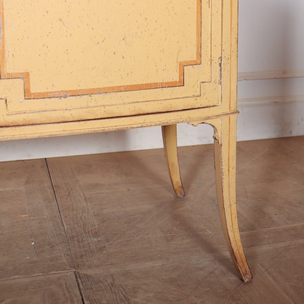 An antique English painted side cabinet in pale yellow with geometric orange door borders and tapered legs. View VI