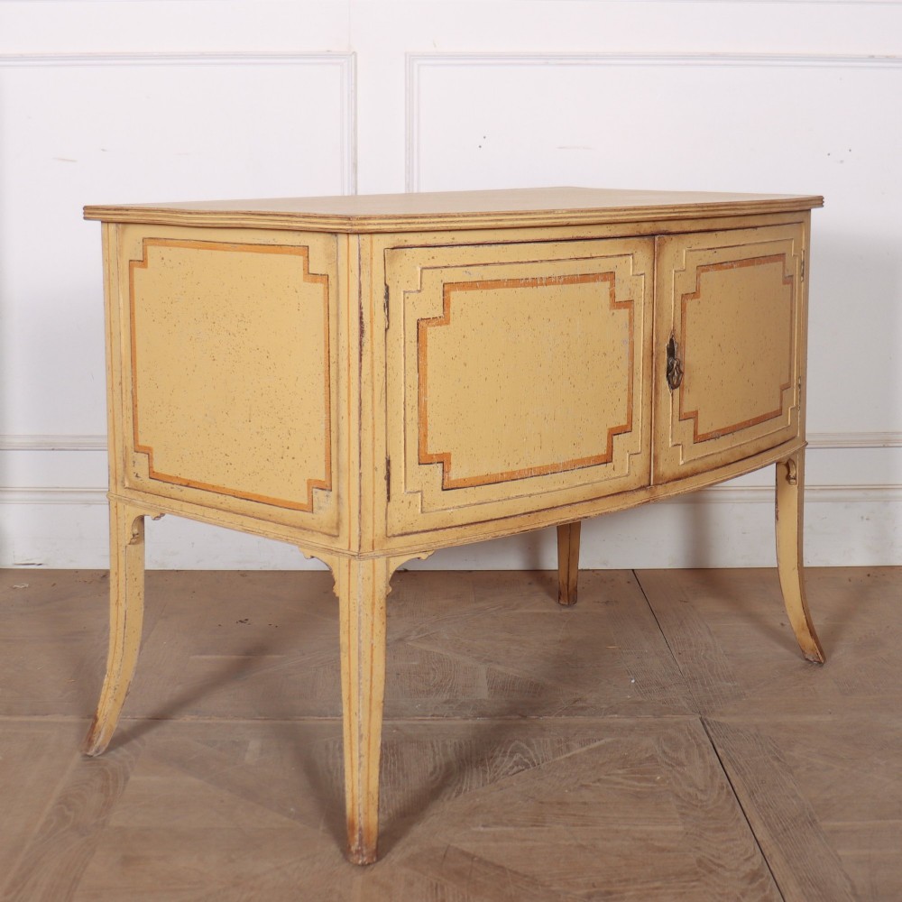 An antique English painted side cabinet in pale yellow with geometric orange door borders and tapered legs. View X