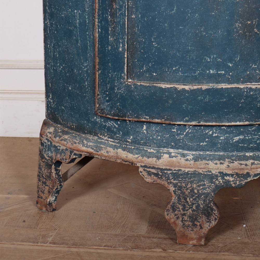 A tall Swedish bowfronted corner cupboard with a distressed blue painted finish, featuring upper and lower panel doors with an open middle shelf. View V