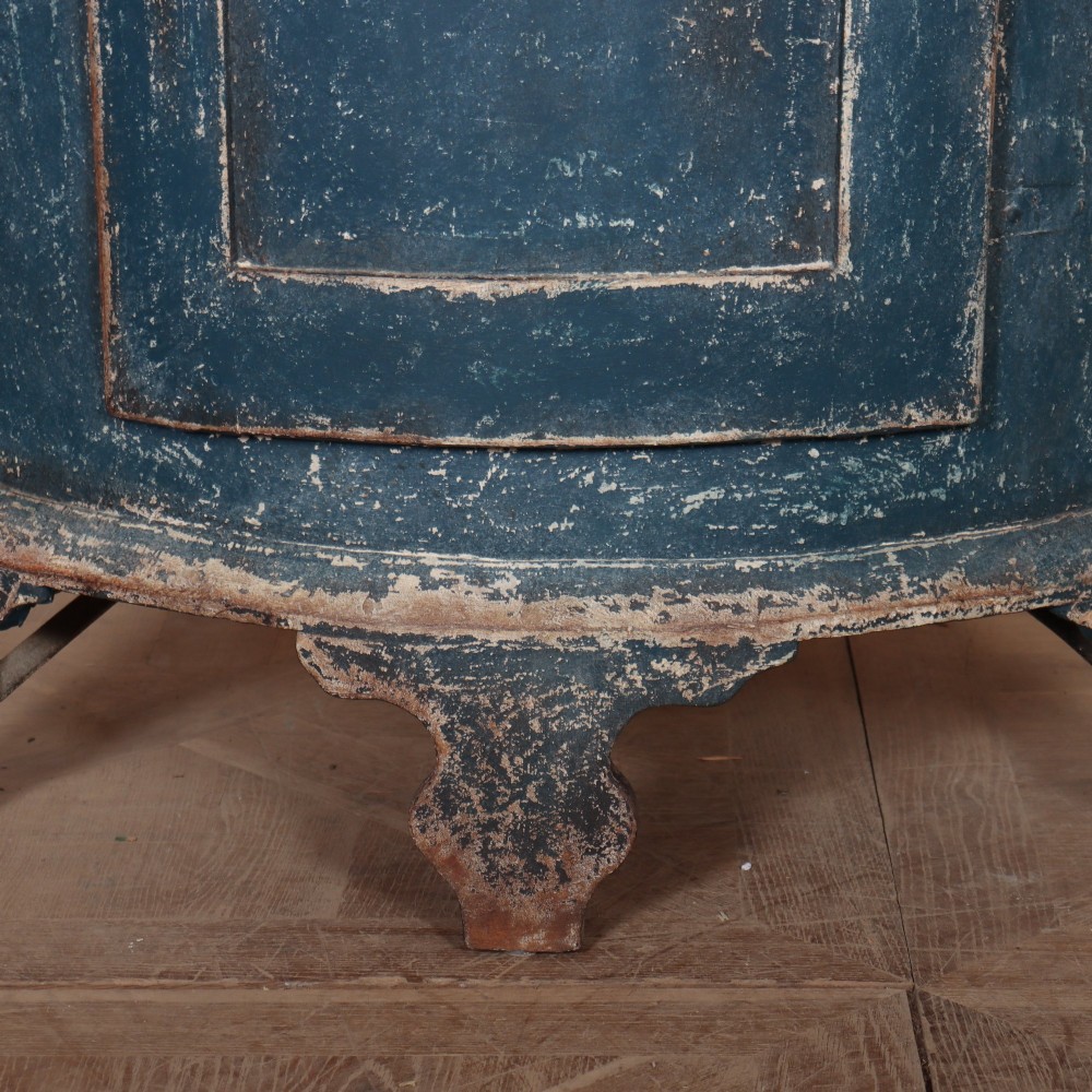 A tall Swedish bowfronted corner cupboard with a distressed blue painted finish, featuring upper and lower panel doors with an open middle shelf. View VII