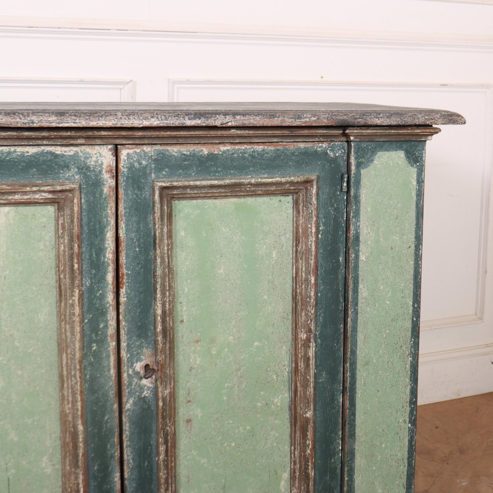 A long rectangular antique Italian side cabinet featuring four panelled doors in a distressed sage and teal painted finish with a plinth base. View V