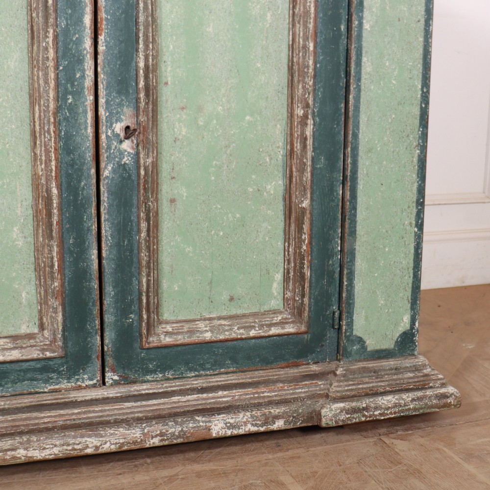 A long rectangular antique Italian side cabinet featuring four panelled doors in a distressed sage and teal painted finish with a plinth base. View VI