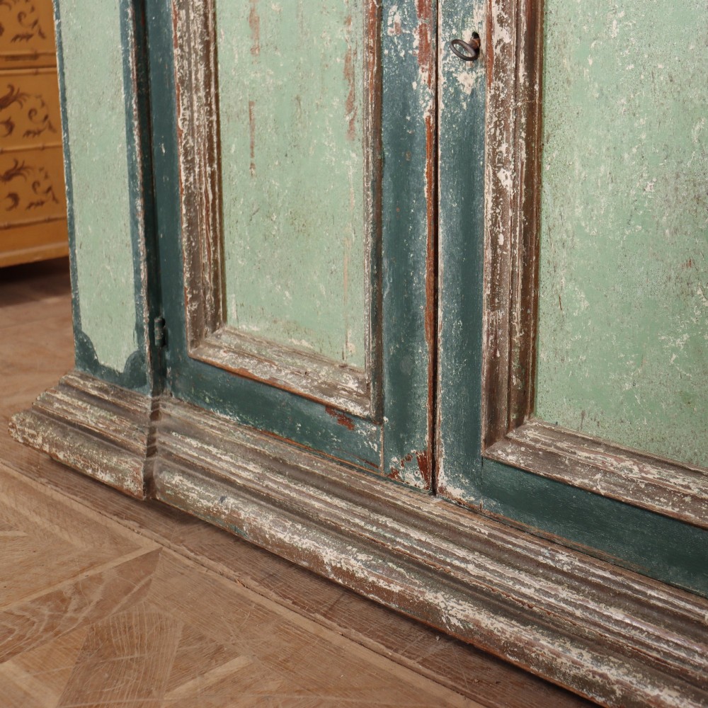 A long rectangular antique Italian side cabinet featuring four panelled doors in a distressed sage and teal painted finish with a plinth base. View VII