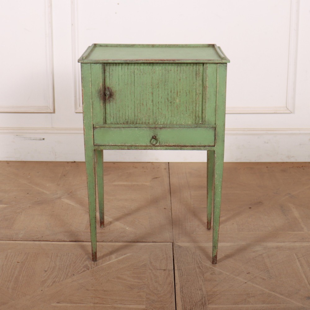 A Dutch provincial green painted bedside table with a slatted tambour door, lower drawer, and tapered square legs.