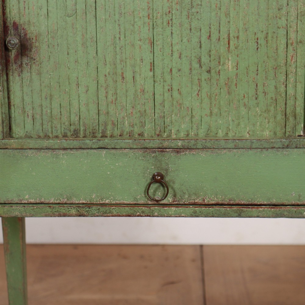 A Dutch provincial green painted bedside table with a slatted tambour door, lower drawer, and tapered square legs. View VI
