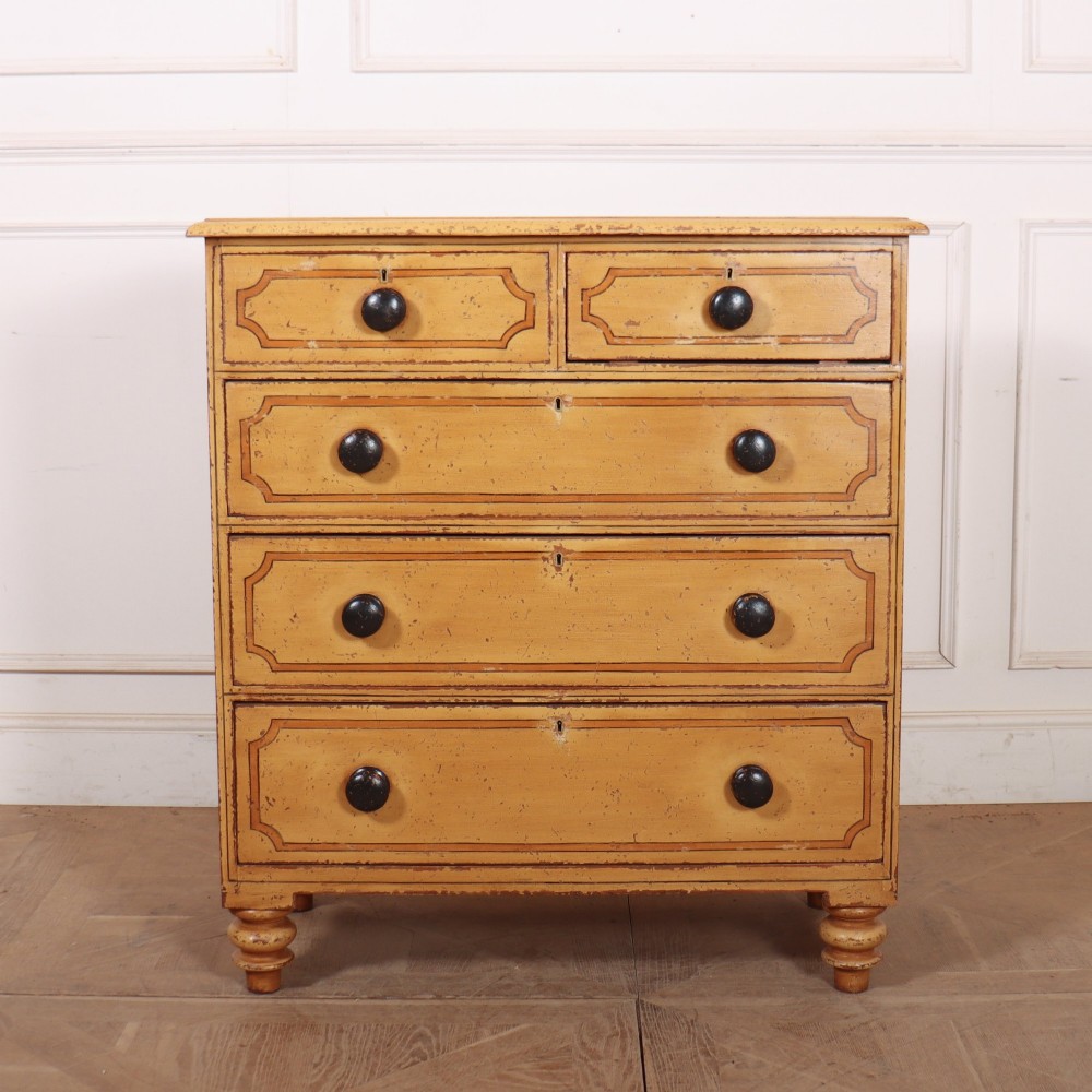 An antique yellow painted pine chest of drawers with two small drawers over three full-width drawers, featuring dark line border detailing, timber knobs, and turned feet.